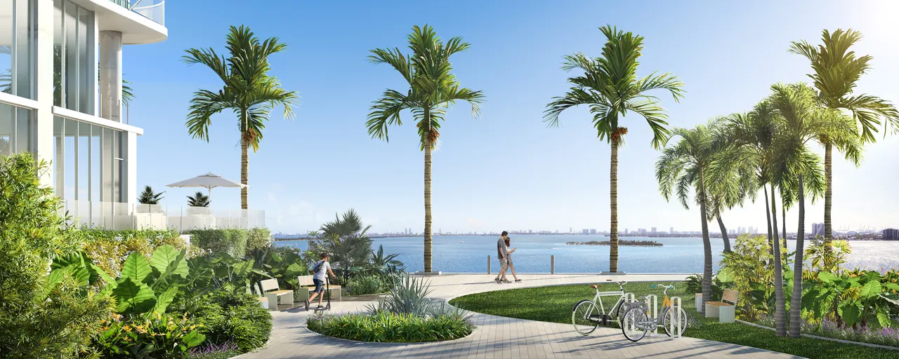 Waterfront promenade with palms, tropical landscaping and bicycles beside a tower's glass base