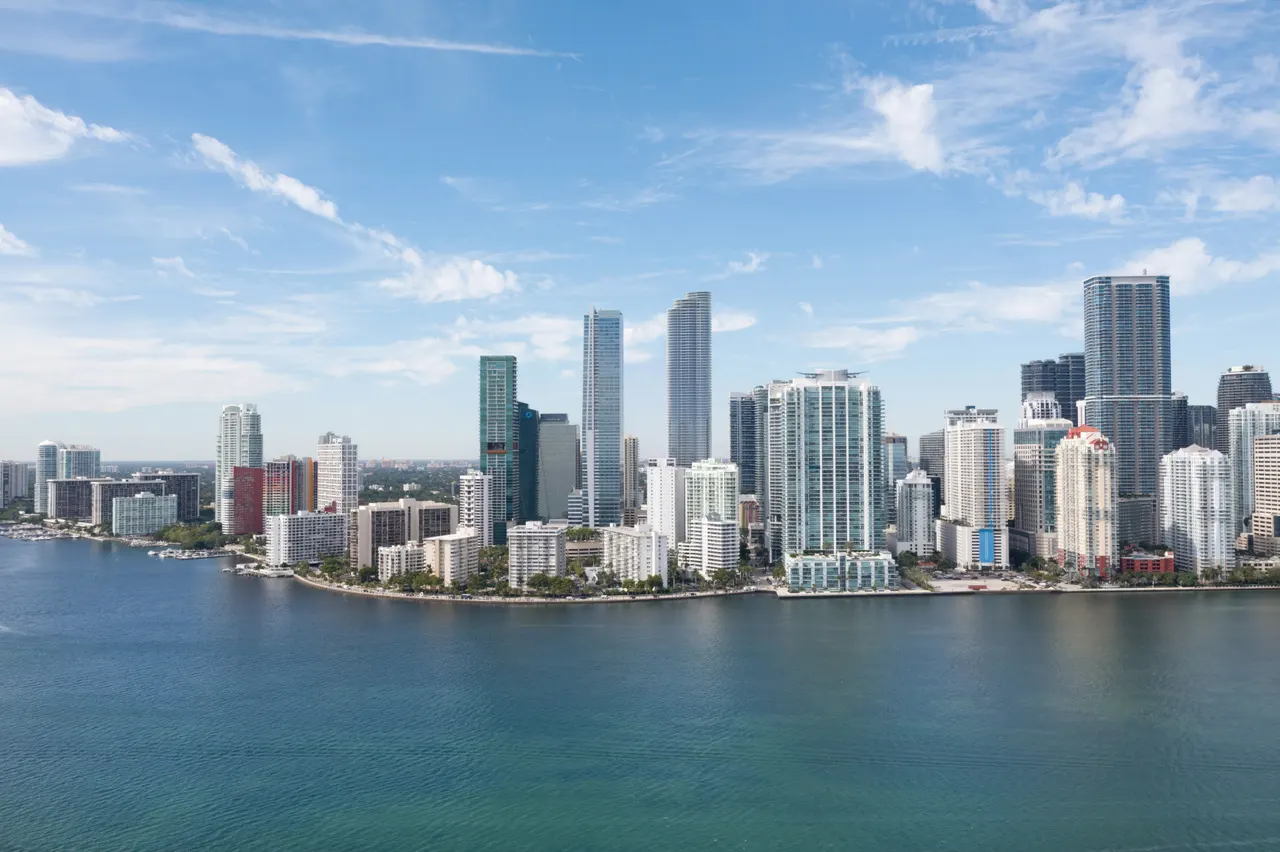Aerial view of the Brickell skyline with waterfront high-rise towers under a clear blue sky