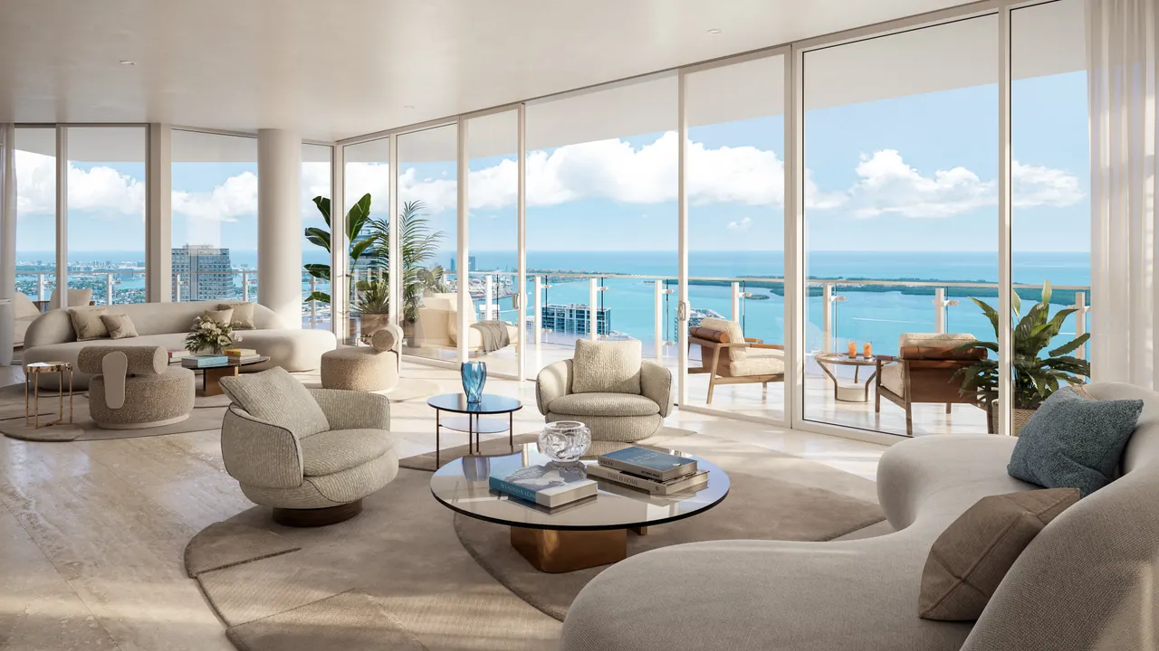Corner living room with curved cream seating and floor-to-ceiling glass opening to a water view