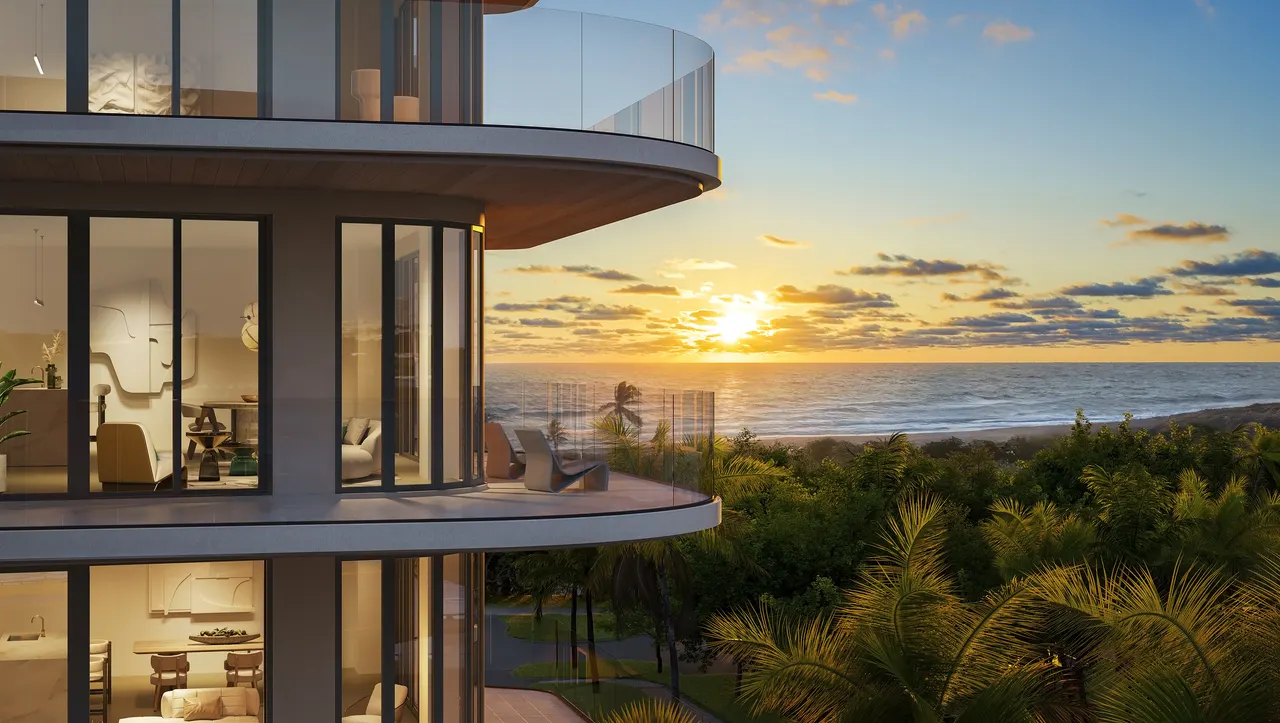 Curved glass balconies of an oceanfront tower overlooking the beach and palms at sunset
