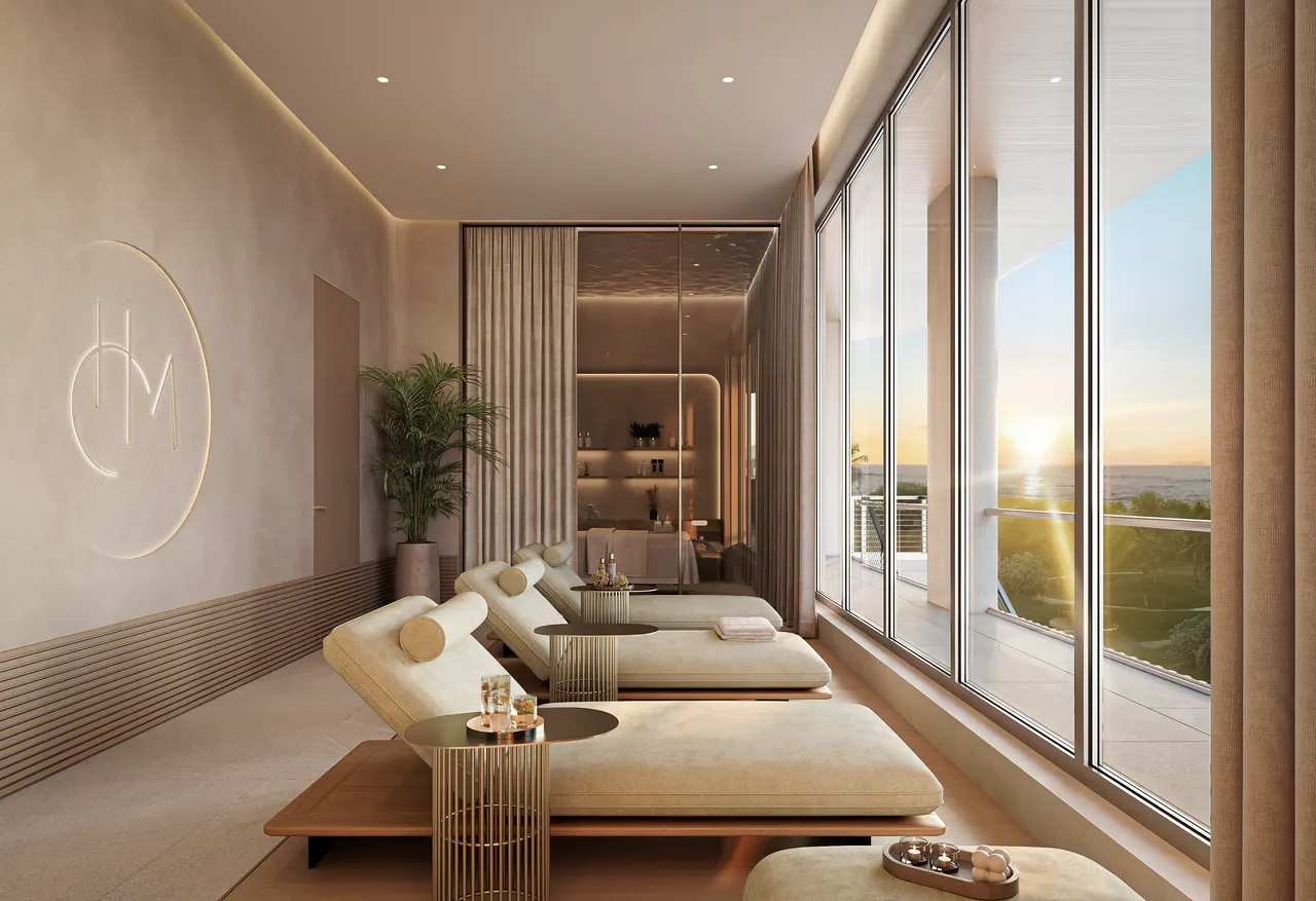 Spa relaxation room with cream loungers, side tables and floor-to-ceiling windows at sunset