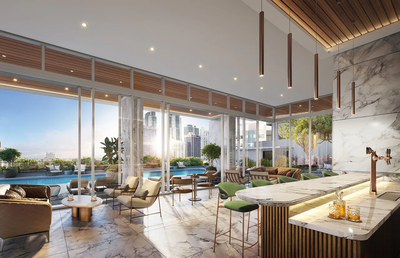 Indoor club lounge with marble bar, green stools and glass walls opening to the pool deck and skyline