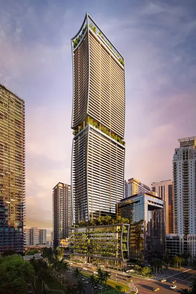 Curved glass tower rising above a landscaped podium and surrounding Brickell high-rises at dawn