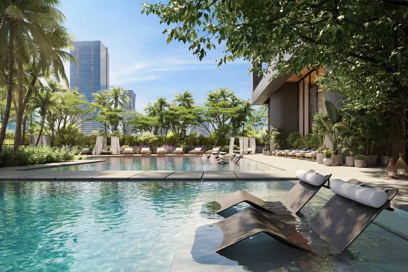 Resort-style pool deck with in-water loungers, palms and cabanas beneath city towers