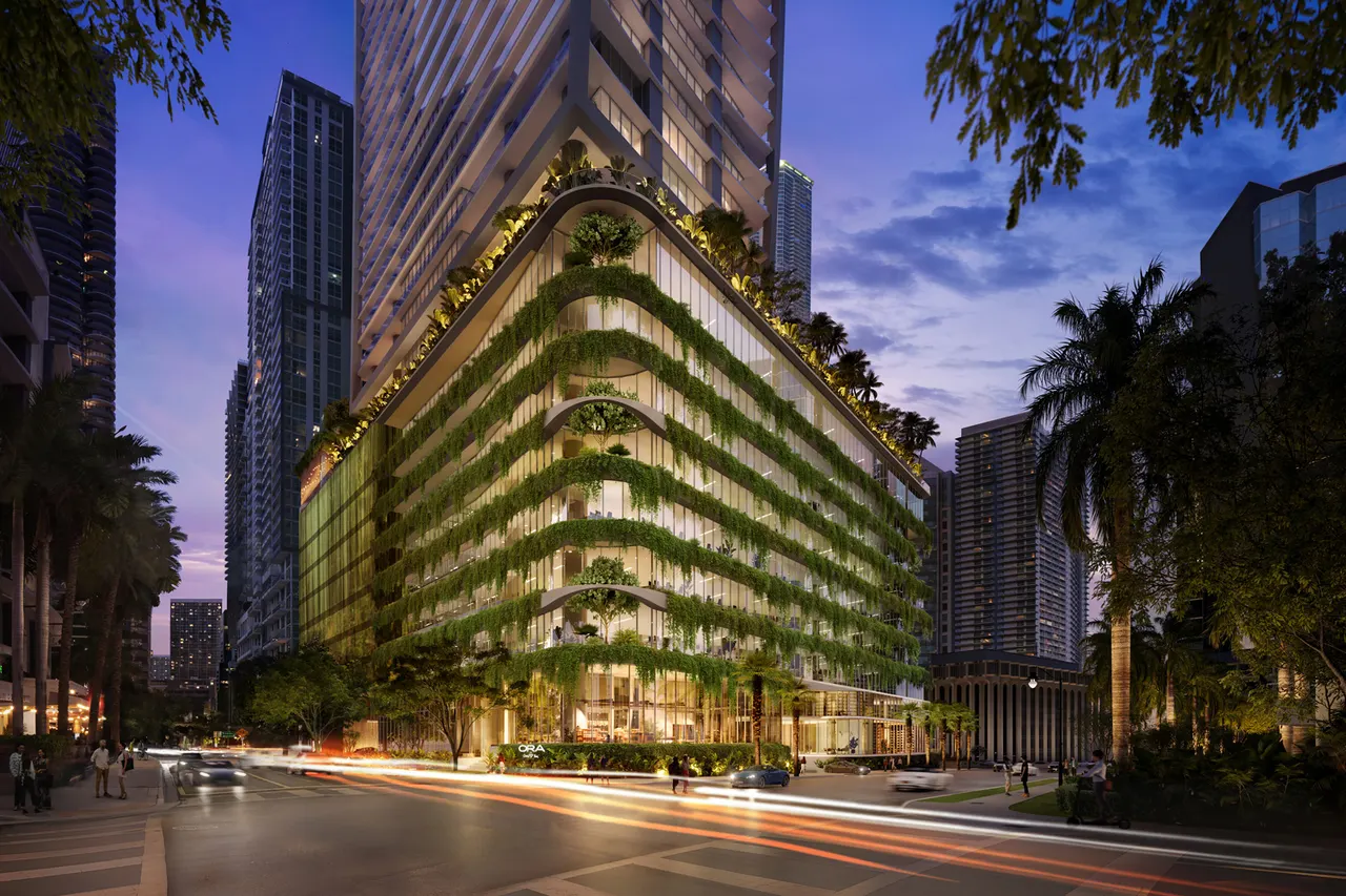 Illuminated tower base with cascading planted terraces above a busy street corner at dusk
