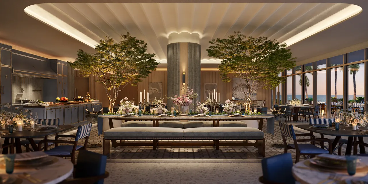 Private dining room with long communal table, indoor trees and open kitchen beside floor-to-ceiling windows