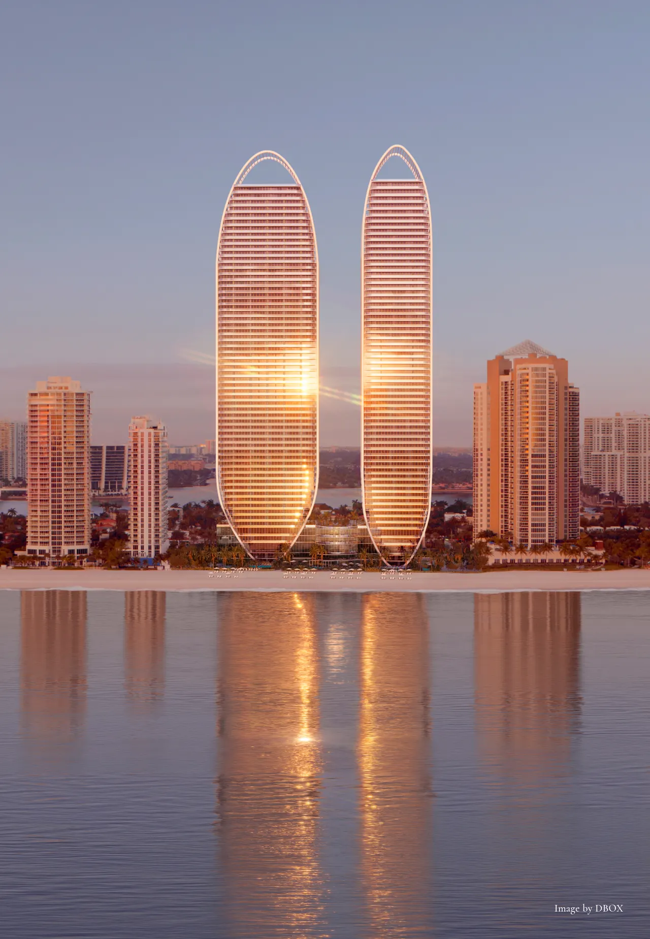 Twin curved oceanfront towers glowing at sunset above the beach, mirrored in calm water