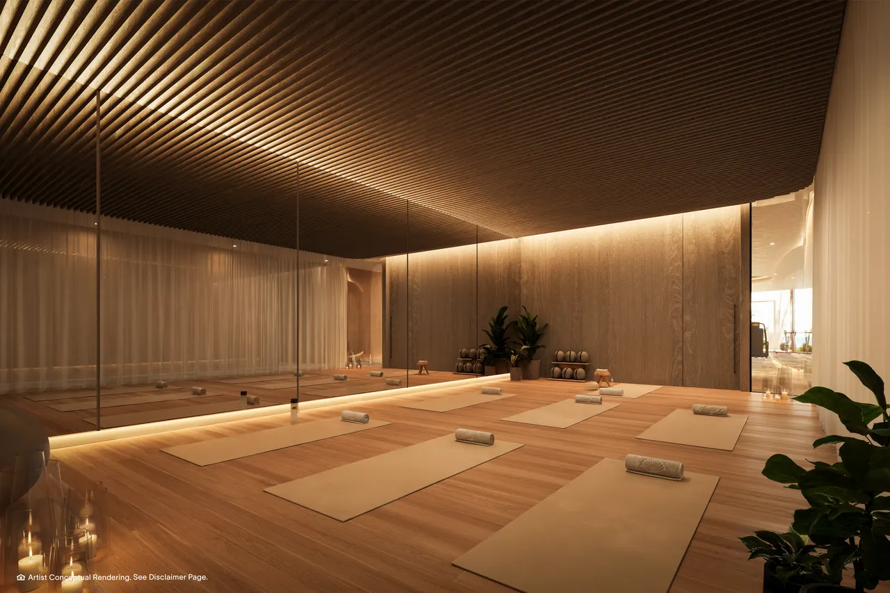 Yoga studio with mats on wood floors, mirrored wall and slatted wood ceiling with warm lighting