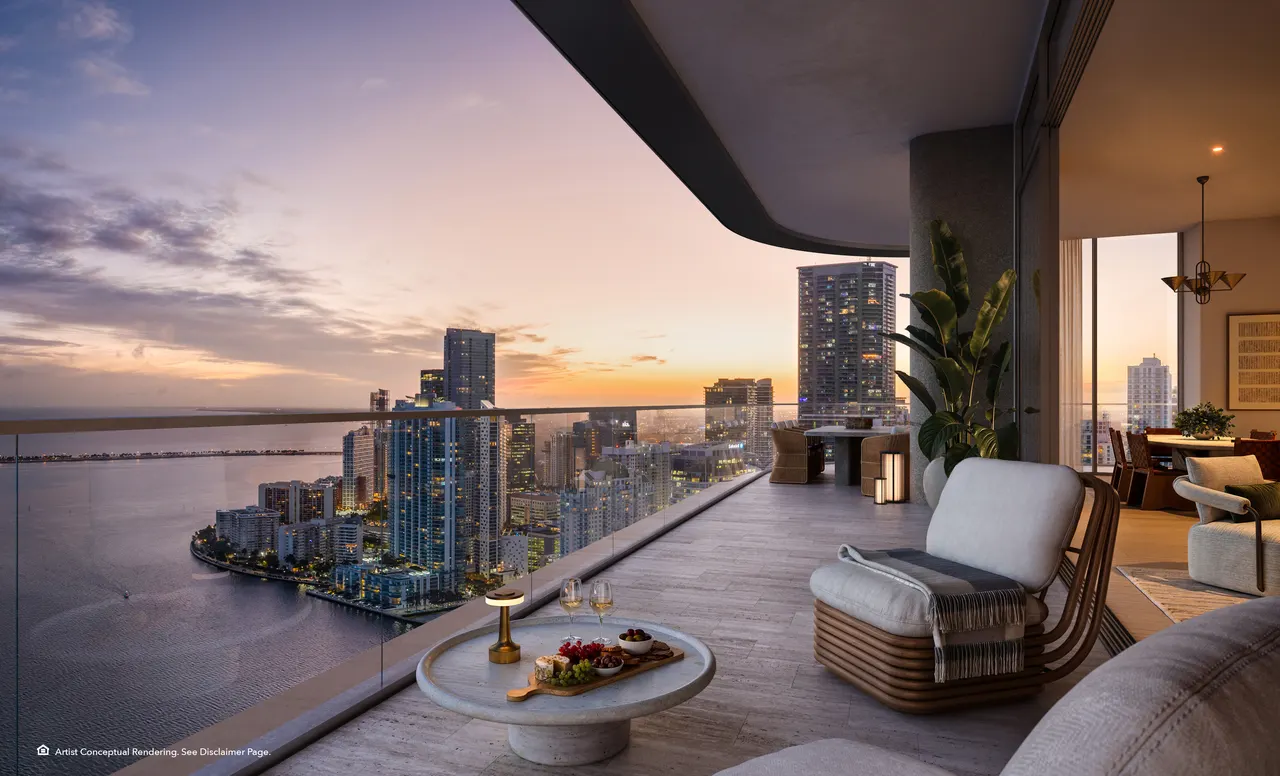 Wraparound terrace with lounge seating and glass railing overlooking the skyline and water at sunset