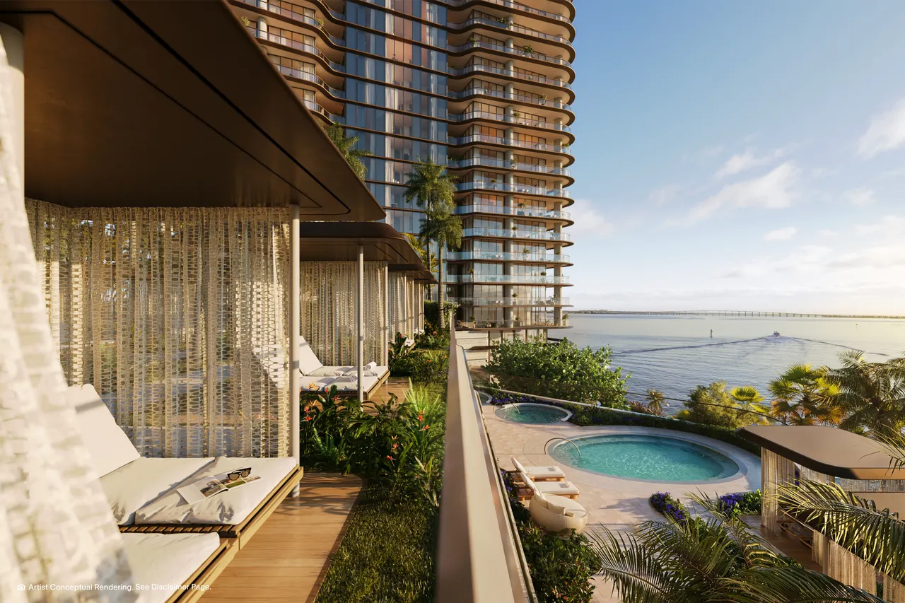 Shaded garden cabanas with daybeds beside circular pools and a waterfront tower terrace