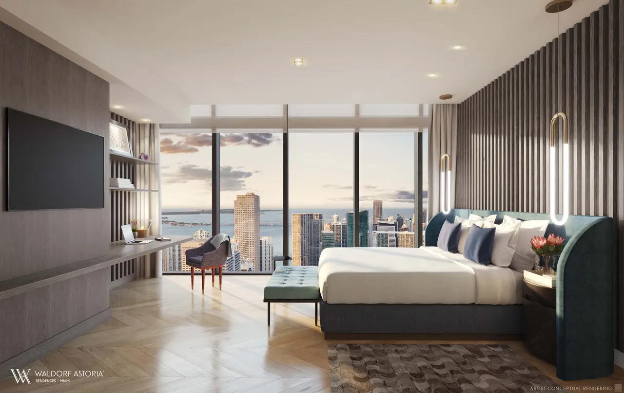 Primary bedroom with teal upholstered headboard, wall-mounted TV and floor-to-ceiling windows over the skyline