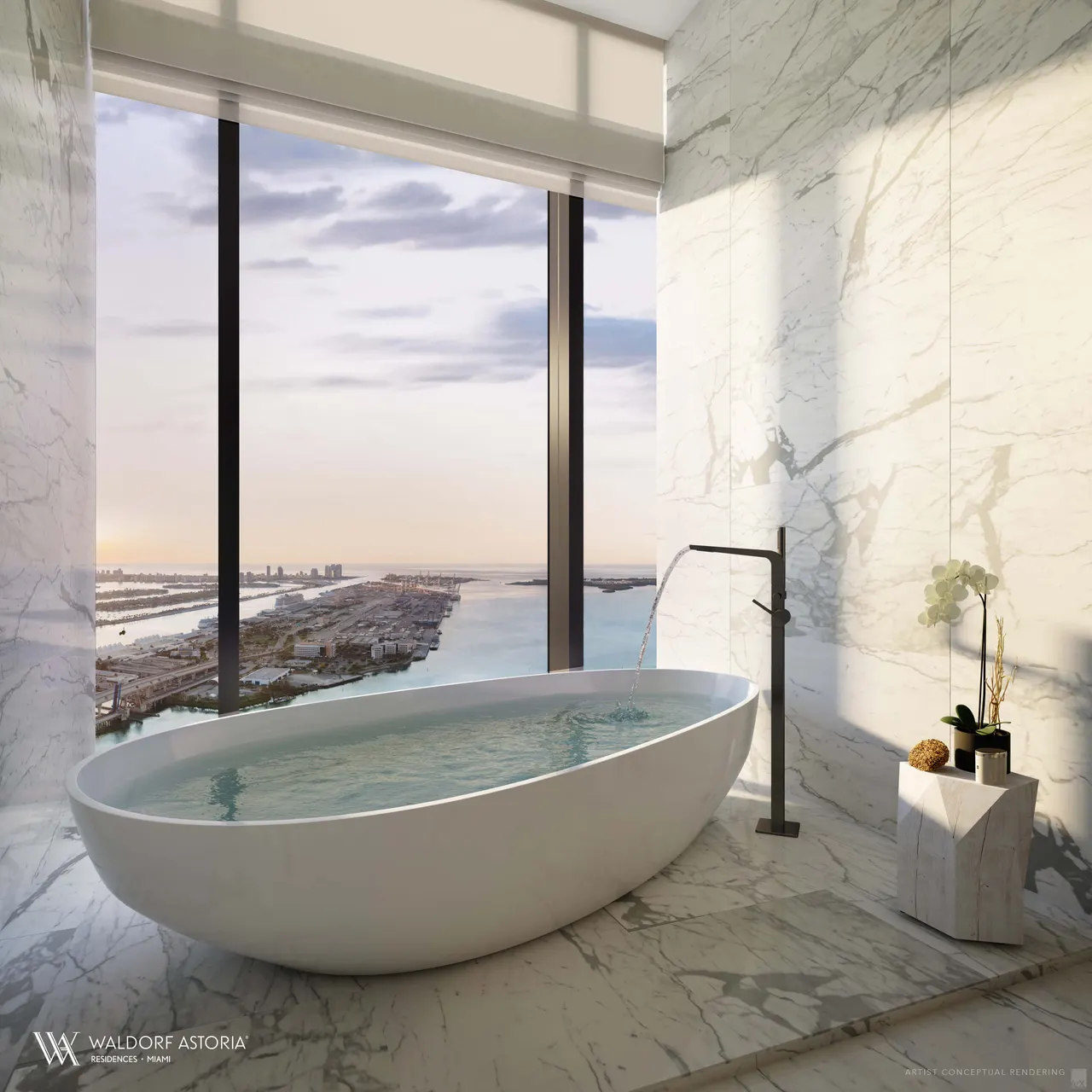 Freestanding soaking tub in a marble primary bathroom with floor-to-ceiling windows over the water